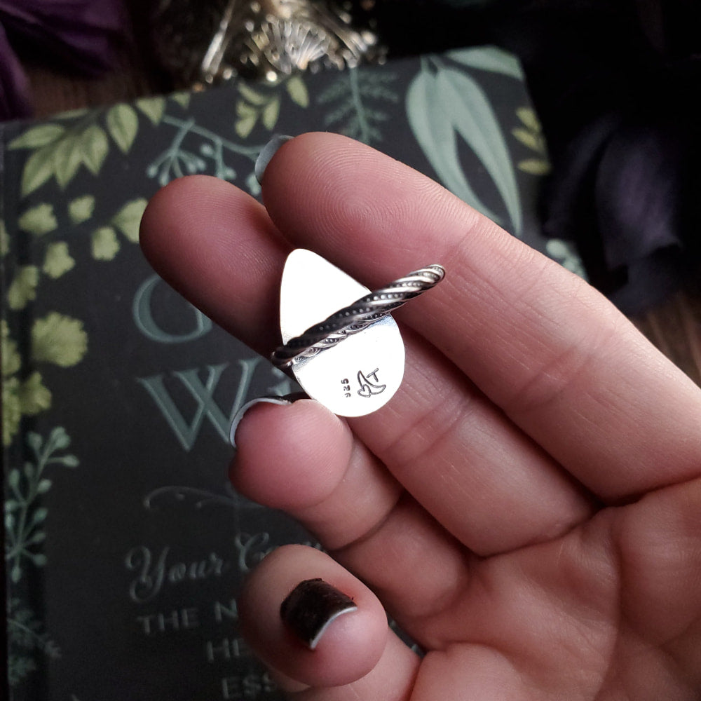 a person holding a silver ring with a heart