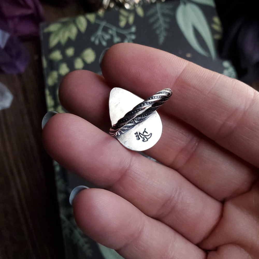 a person holding a silver ring with a bird on it