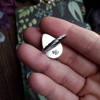 a person holding a silver ring with a bird on it