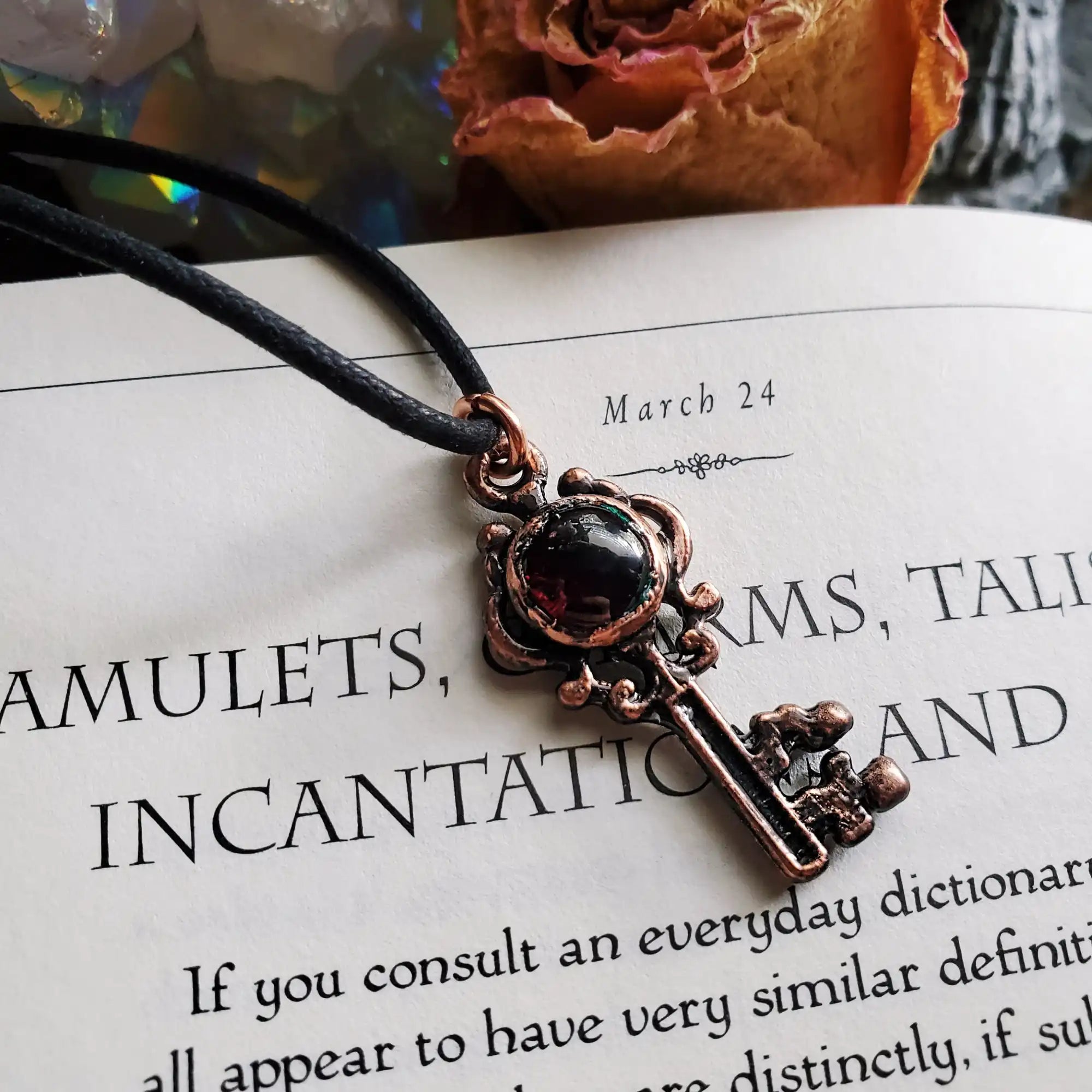 An antique-style bronze key pendant with a black gemstone accent.