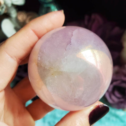 a person holding a large pink quartz ball