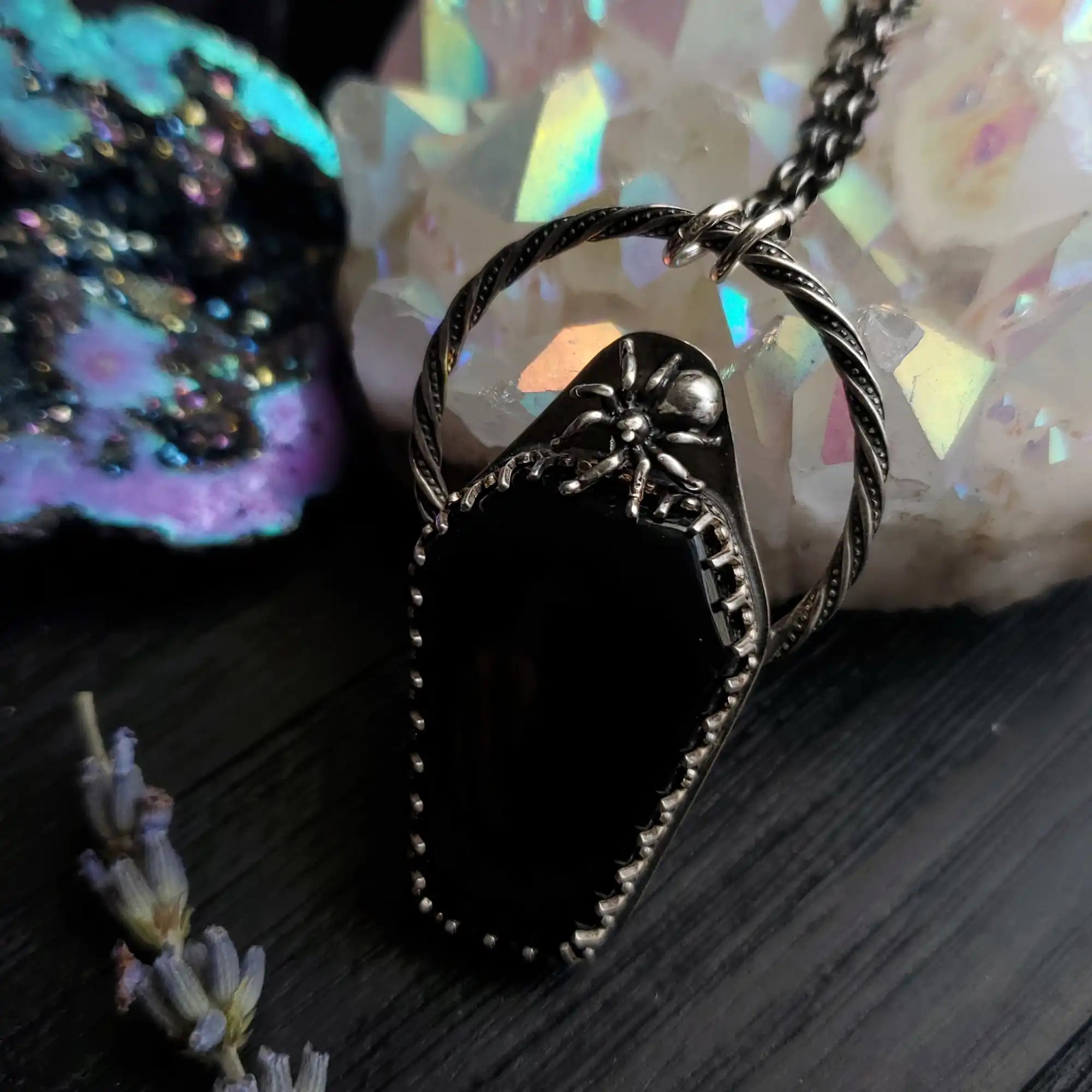 A black coffin-shaped pendant with a spider design, set in a twisted silver-toned metal frame, on a matching chain.