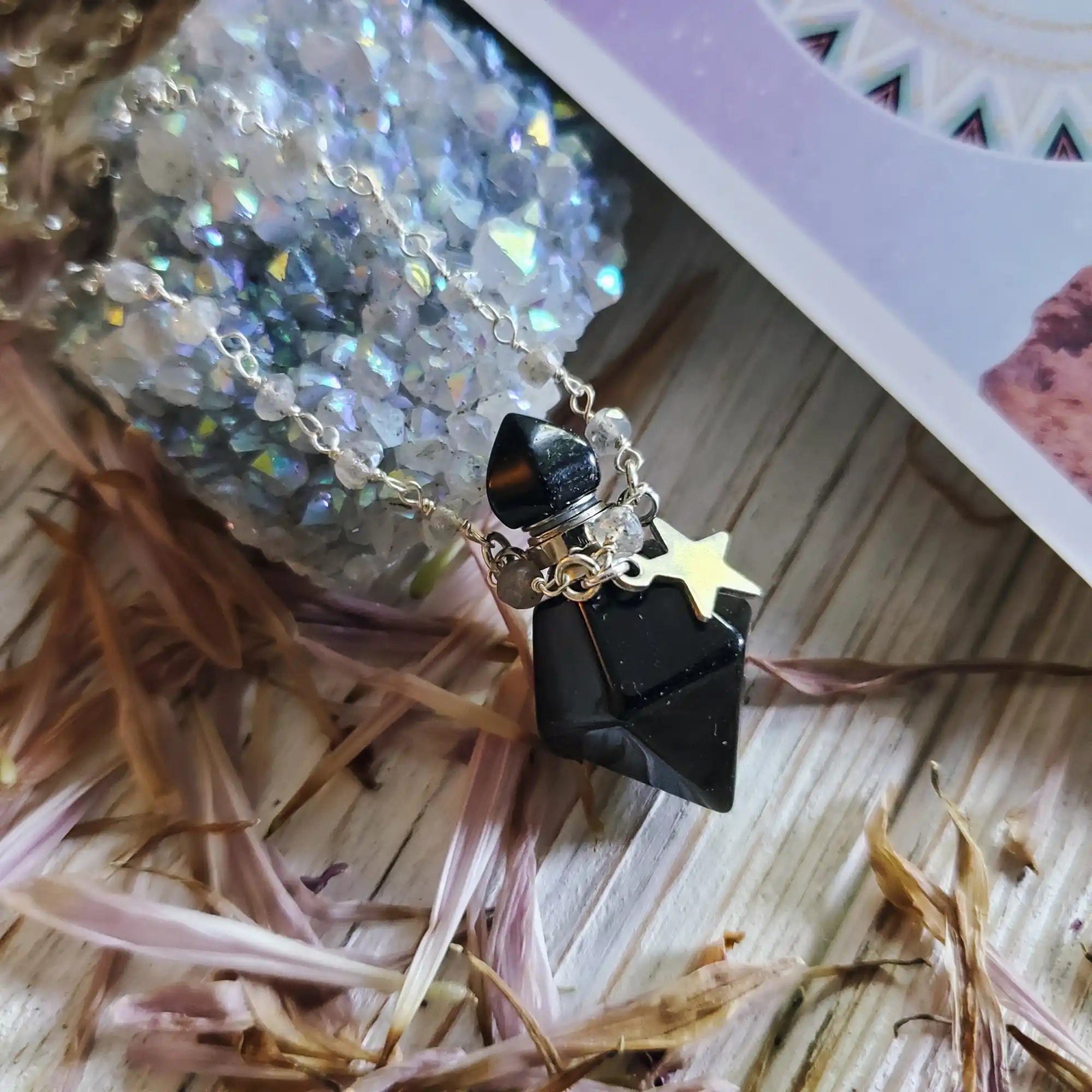Black faceted stone pendant with a gold star charm on a beaded chain.