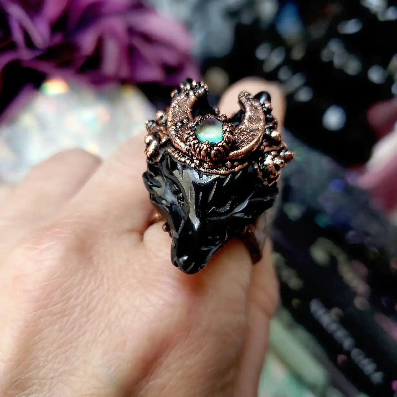 A black wolf-head ring with an ornate copper-colored setting and a glowing central gemstone.