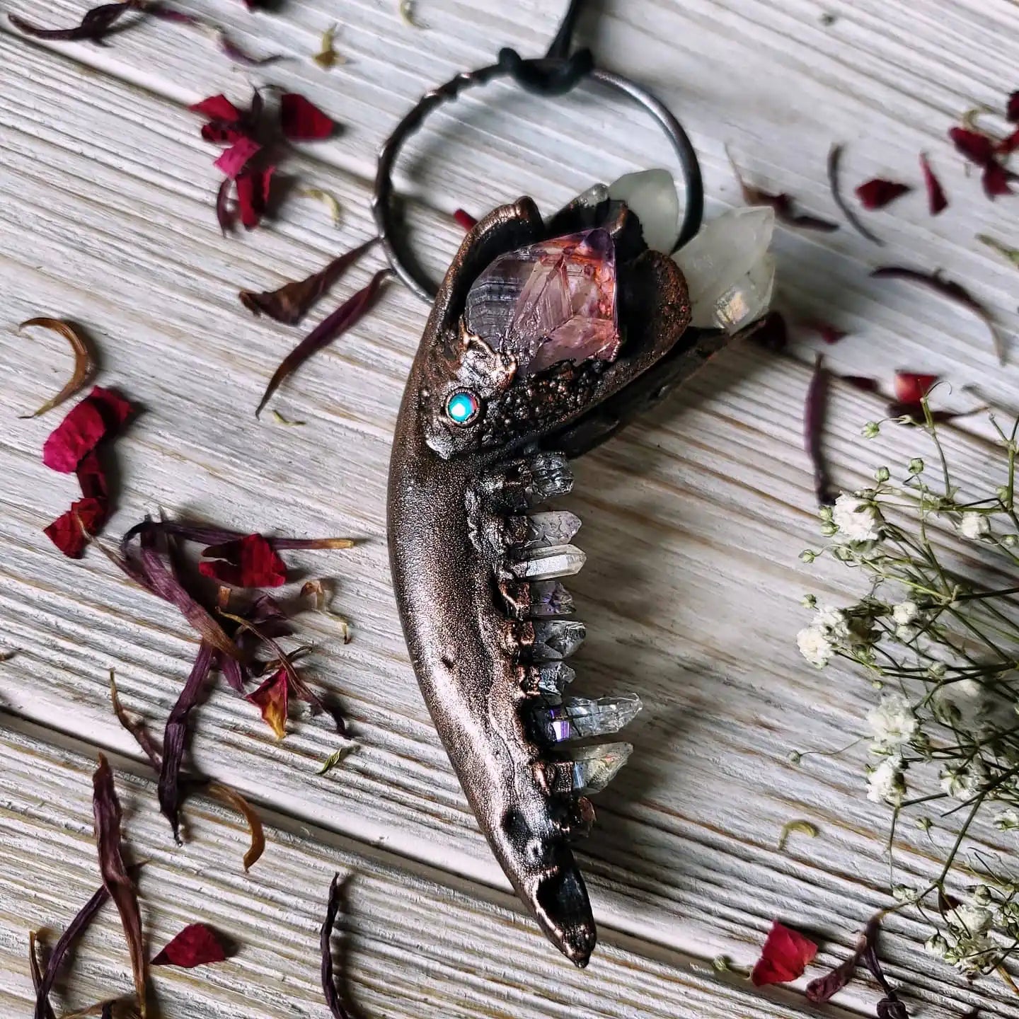 A dark, curved pendant with embedded crystals and a turquoise accent.