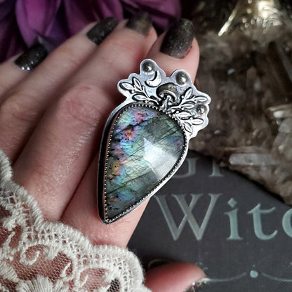 a woman’s hand holding a large stone ring