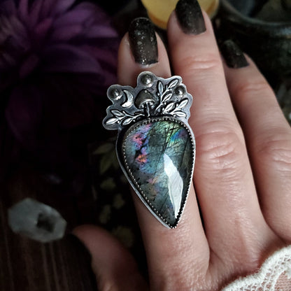 a woman’s hand holding a large heart shaped ring