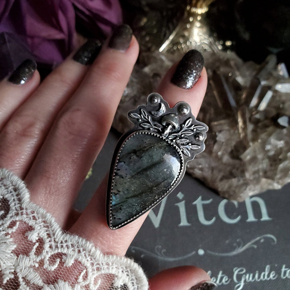 a woman’s hand holding a large black stone ring