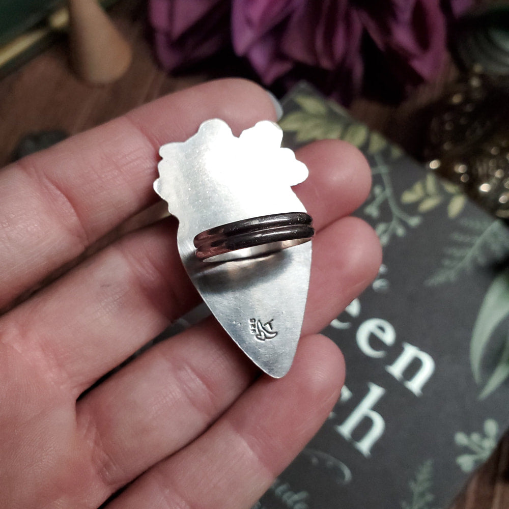 a person holding a silver ring with a bear on it