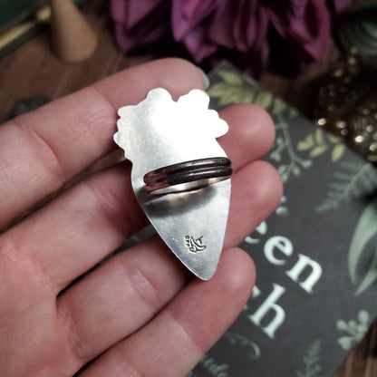 a person holding a silver ring with a bear on it