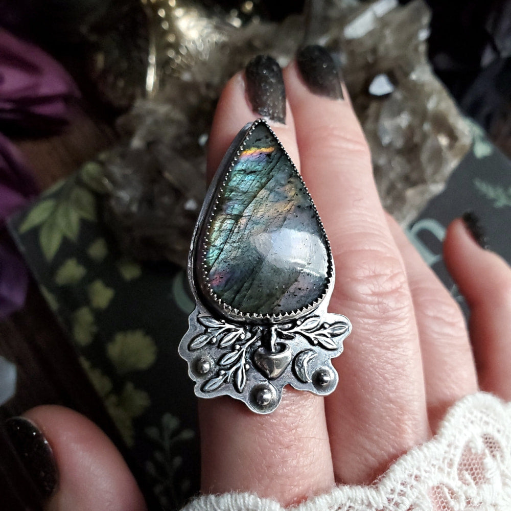 a close up of a person holding a ring with a stone