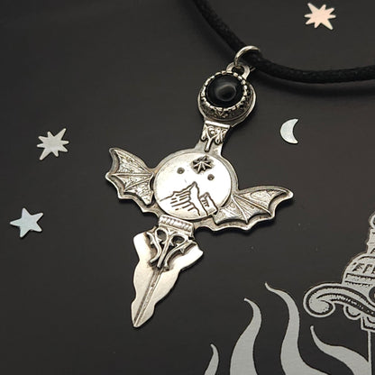Silver bat-winged pendant with black stone.