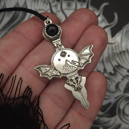 Silver bat-winged pendant with black stone.