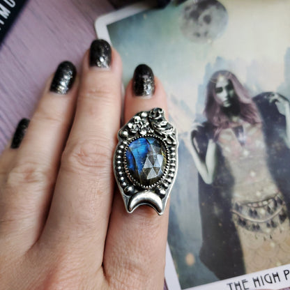 a woman’s hand holding a ring with a blue stone