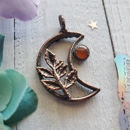 a copper moon with a branch and a star on it