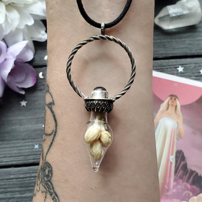 a woman’s hand holding a silver pendant with a white flower