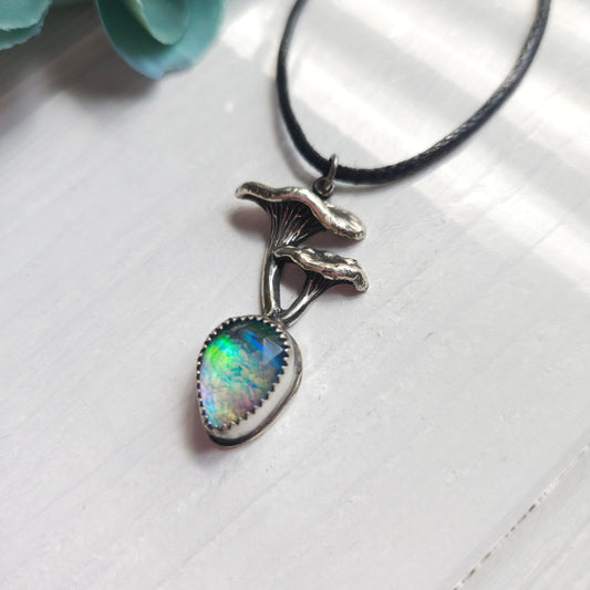 Mushroom-shaped pendant necklace with an iridescent opal-like gemstone.