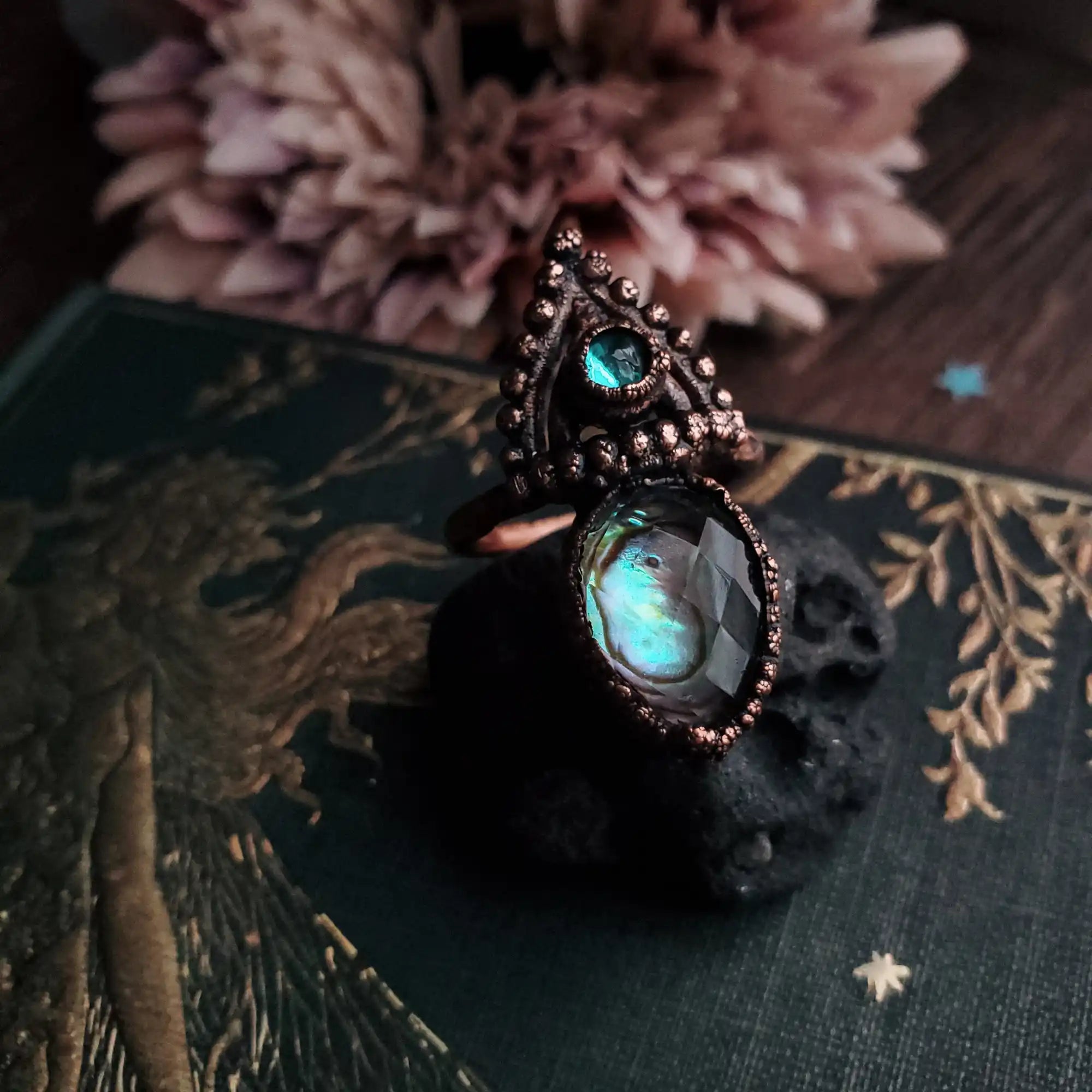 An ornate copper ring with two iridescent, faceted gemstones.