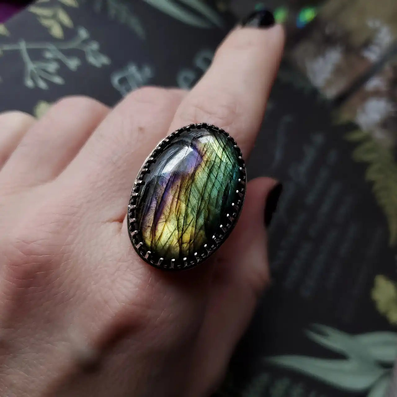 An oval labradorite gemstone ring with an ornate silver-toned setting.