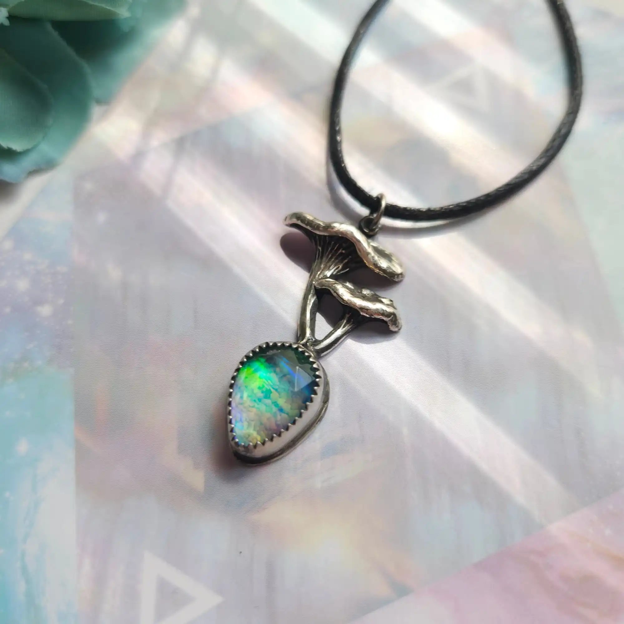 A silver mushroom pendant with an iridescent gemstone.