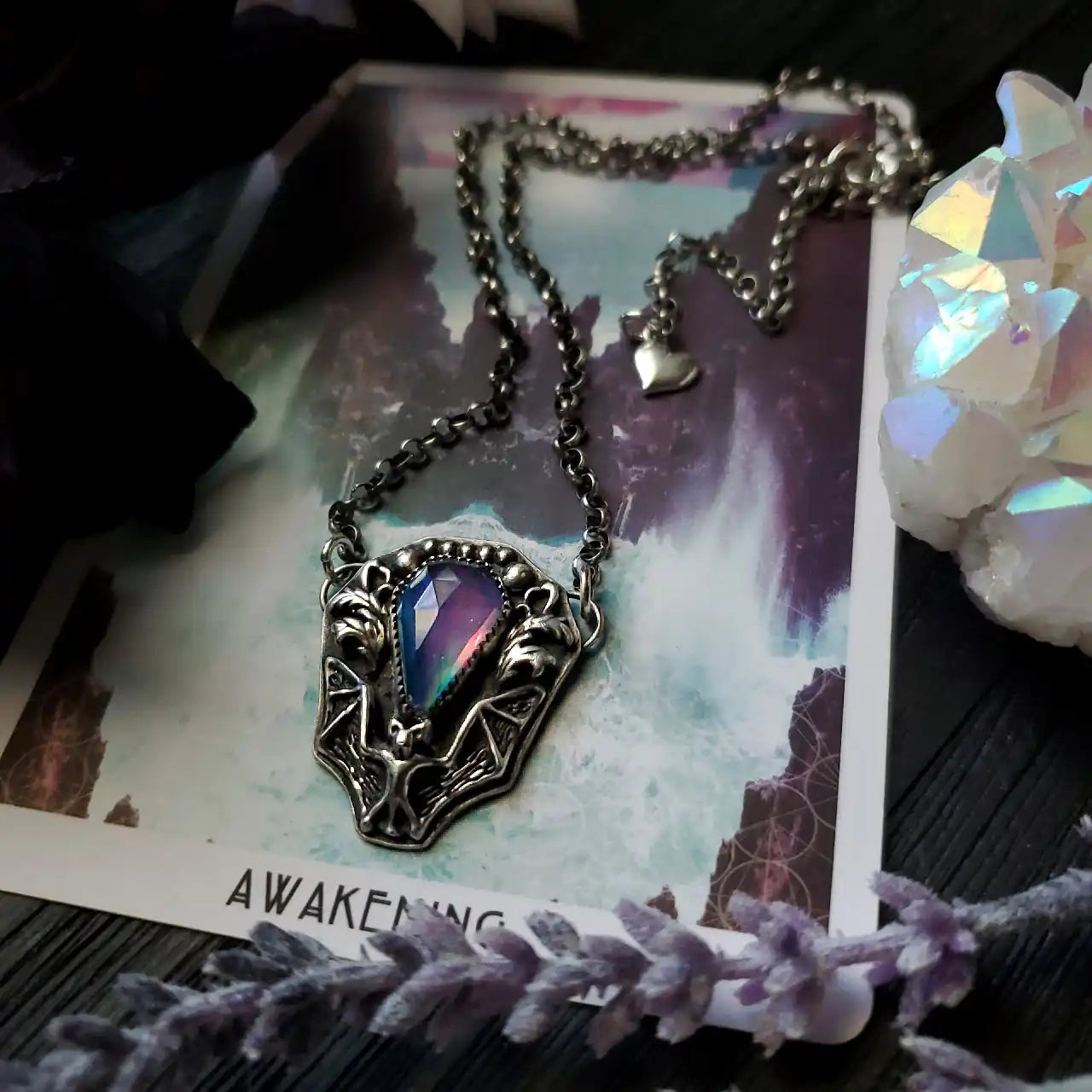 A silver bat-wing pendant with a multi-colored gemstone.
