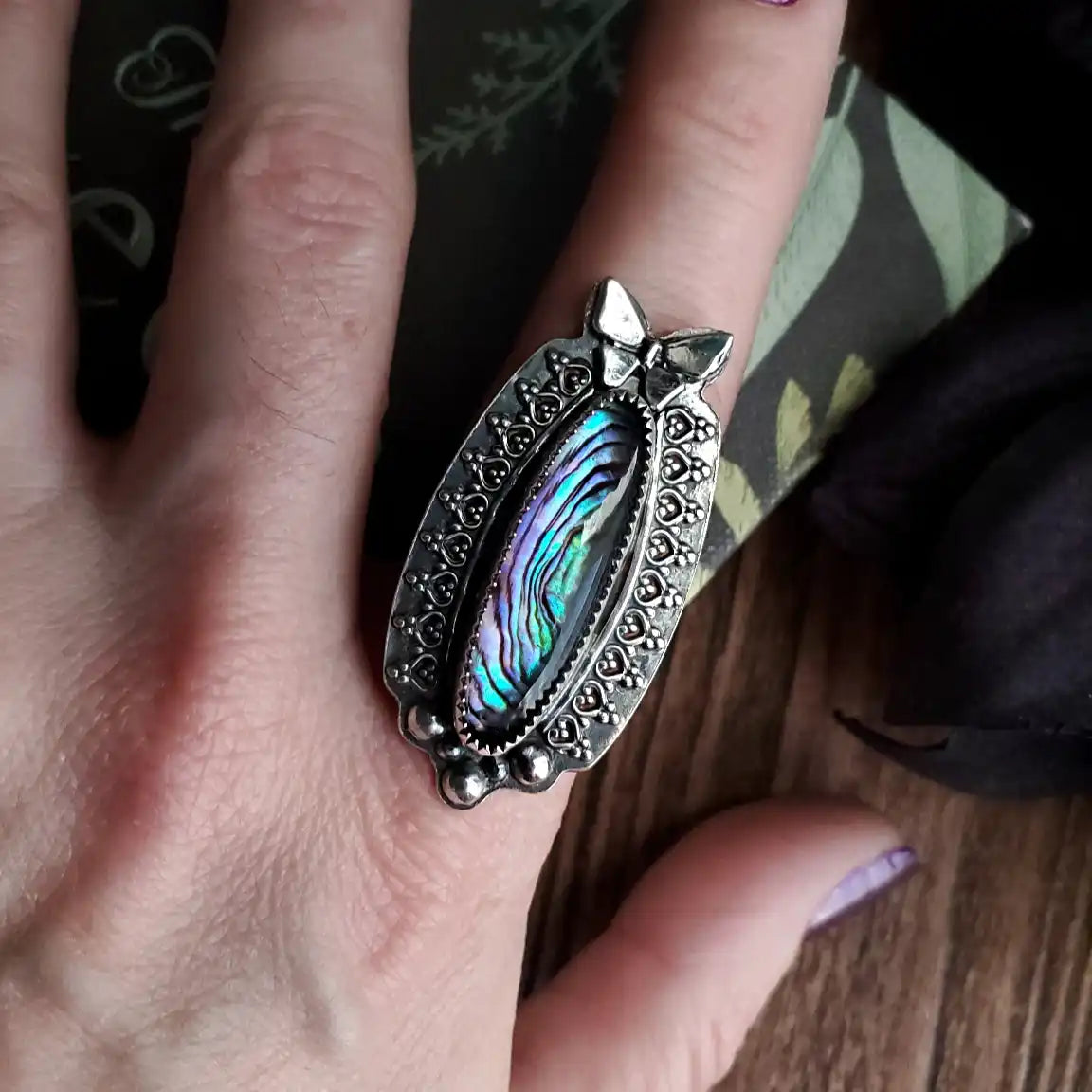 A silver ring with an iridescent abalone shell inlay.