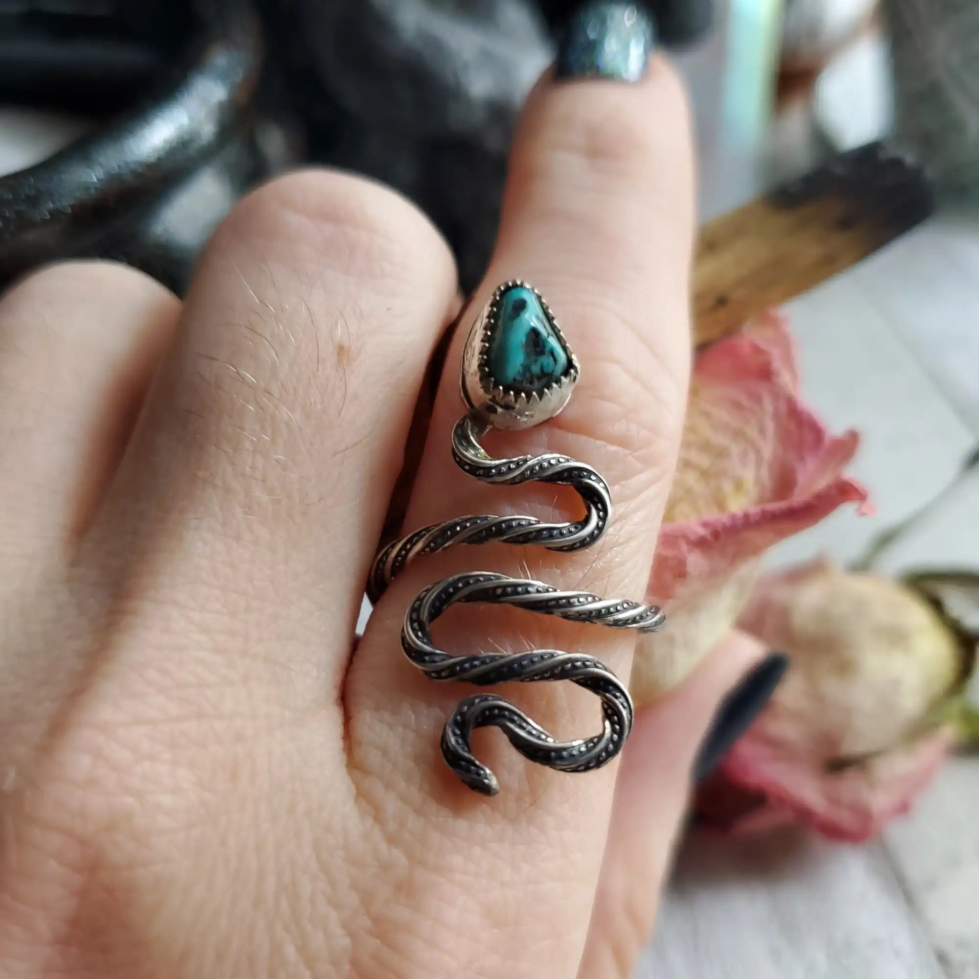 A silver snake-shaped ring with a turquoise gemstone.