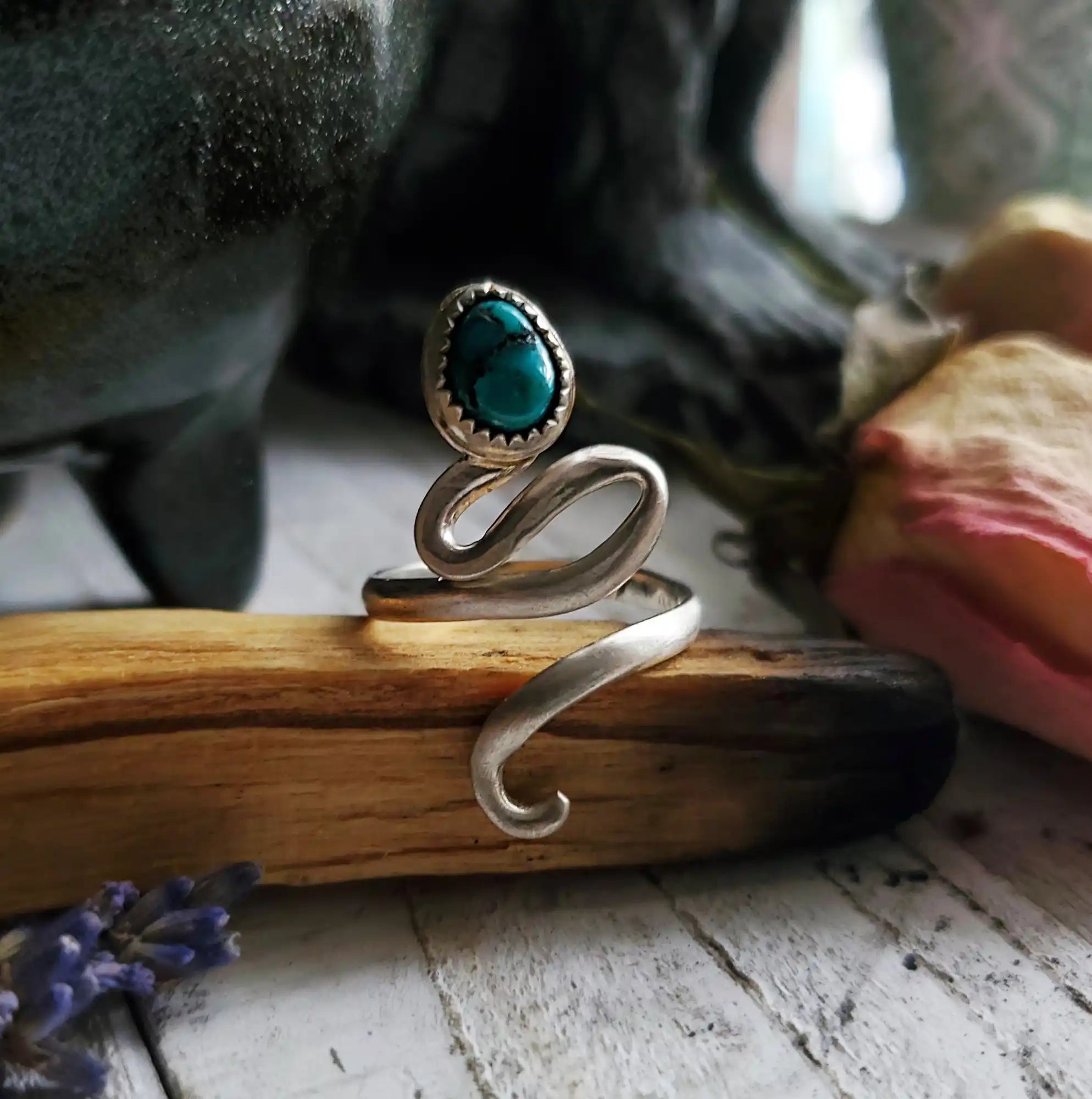 A silver-toned snake ring with a turquoise gemstone.