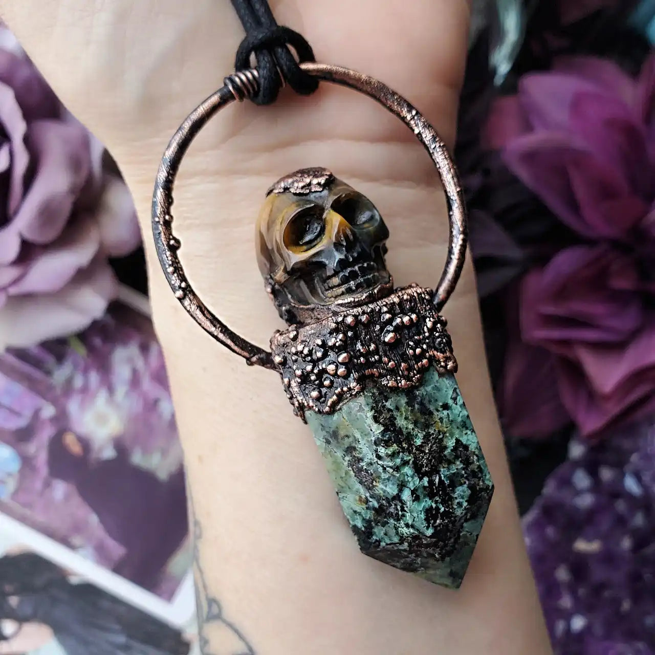 A skull and crystal pendant with an ornate copper setting.