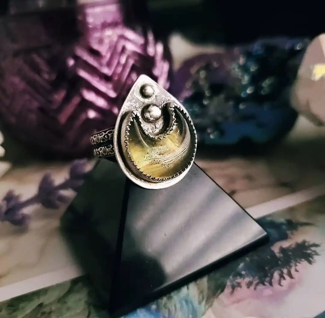 A teardrop-shaped sterling silver ring with a yellow-gold tiger’s eye inlay.
