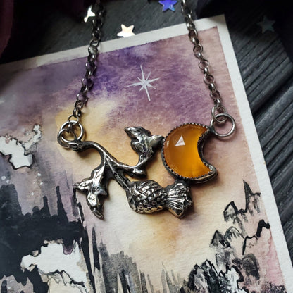 a necklace with a cat and a moon on it