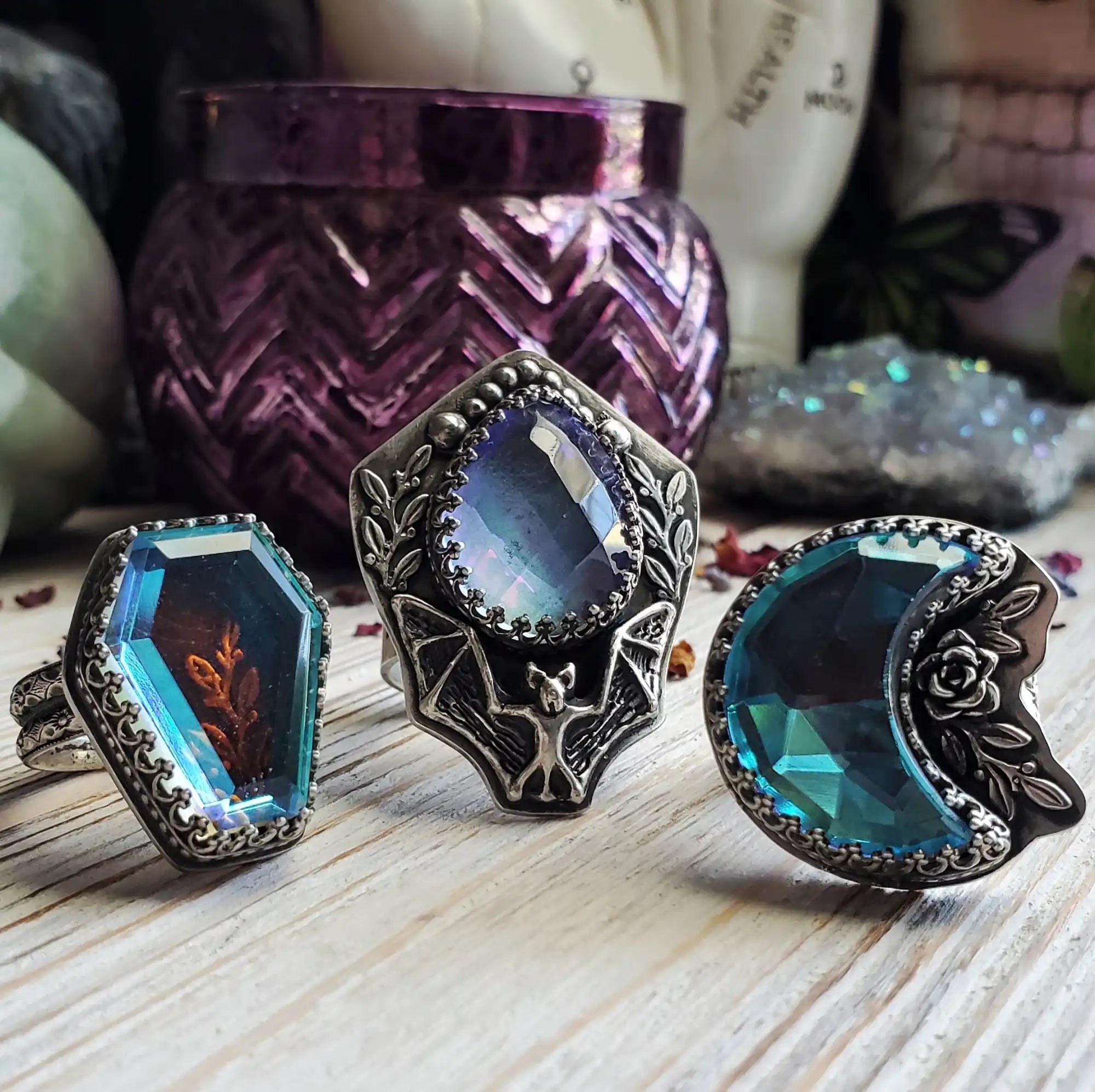 Three intricately designed rings with colorful, faceted stones.