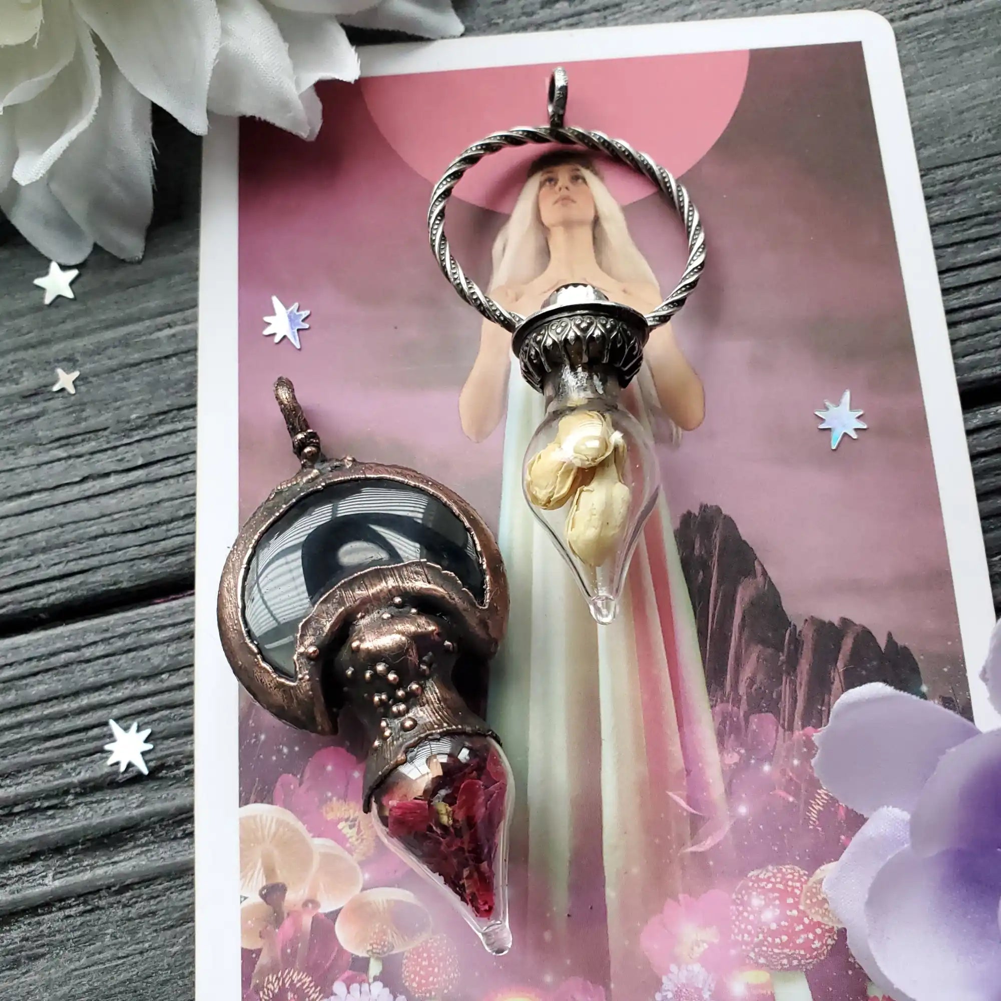 Two ornate glass vial pendants, one with golden shells and the other with red dried flowers.