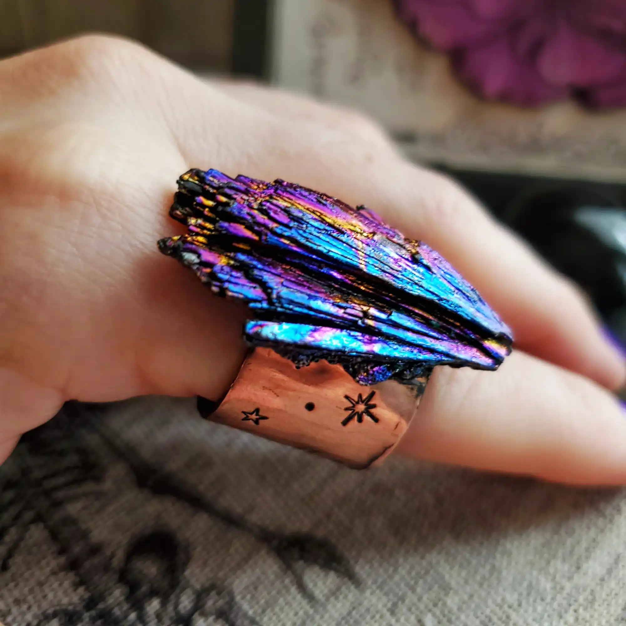 A vibrant, iridescent titanium quartz ring with a copper band featuring celestial engravings.